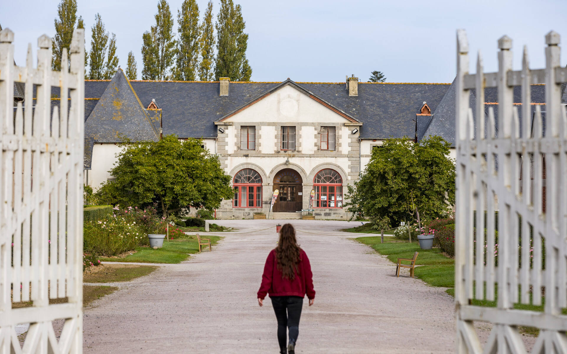 Jeune femme en manteau rouge dans la cours du Haras de Lamballe