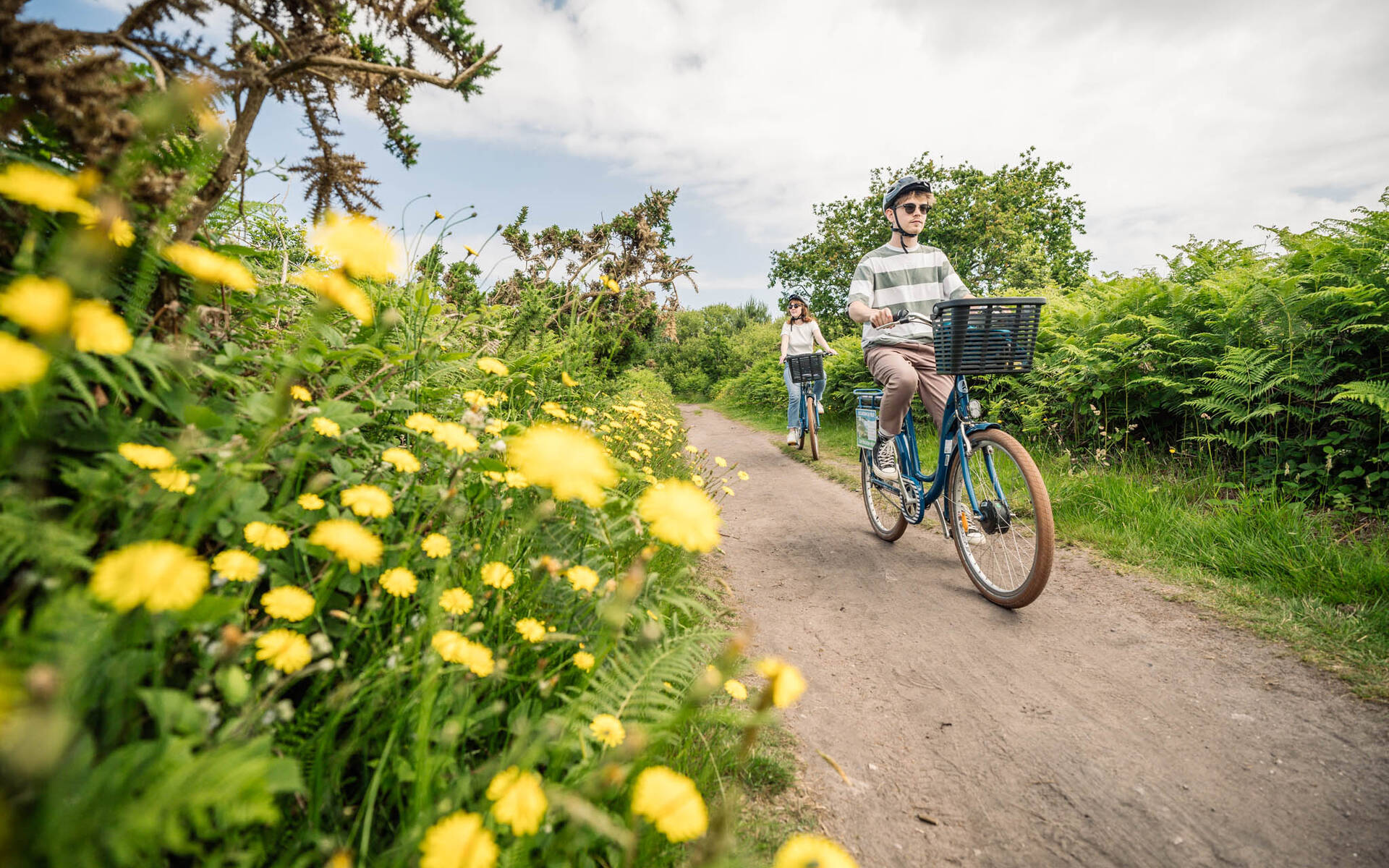Deux adultes à vélo sur un chemin bordé de fleurs