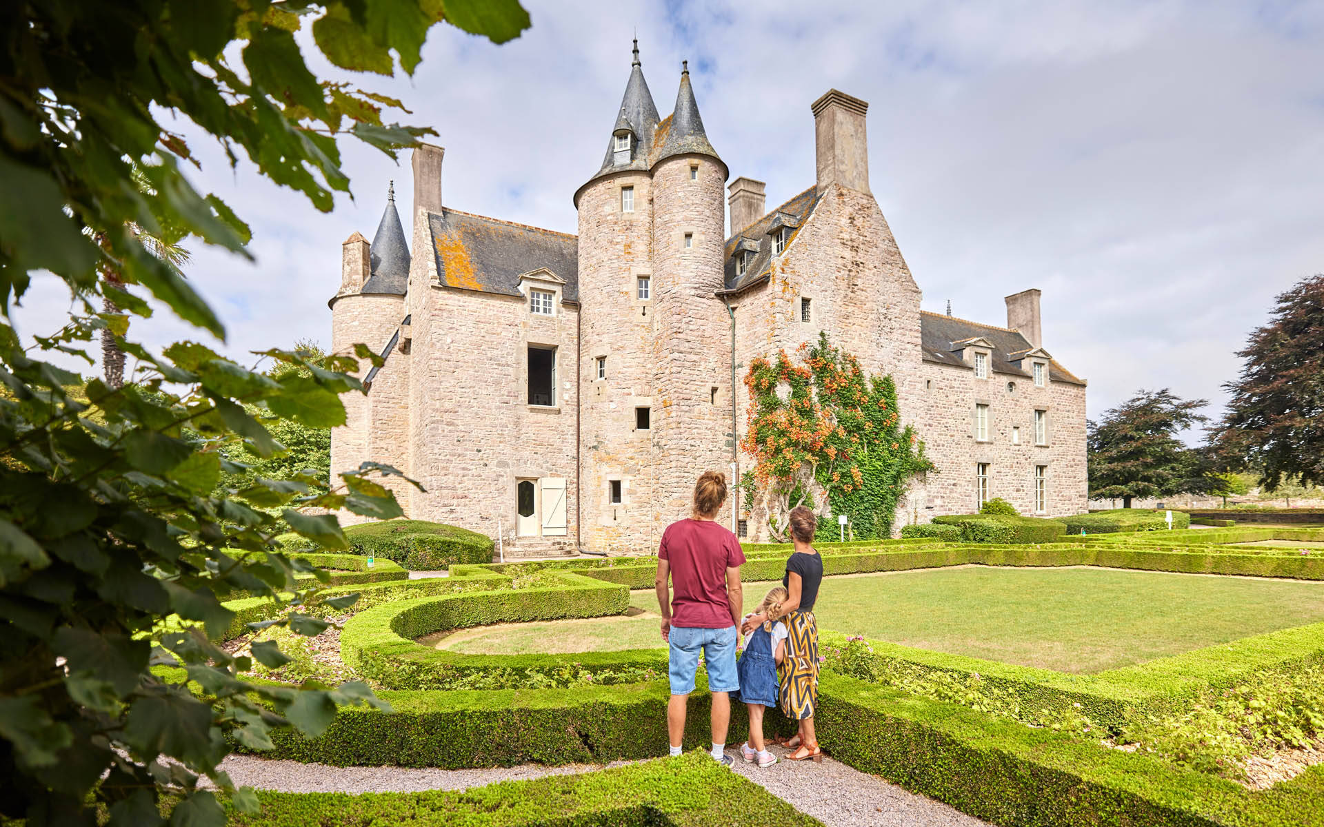 Deux adultes et un enfant regardant le château de Bienassis depuis les jardins