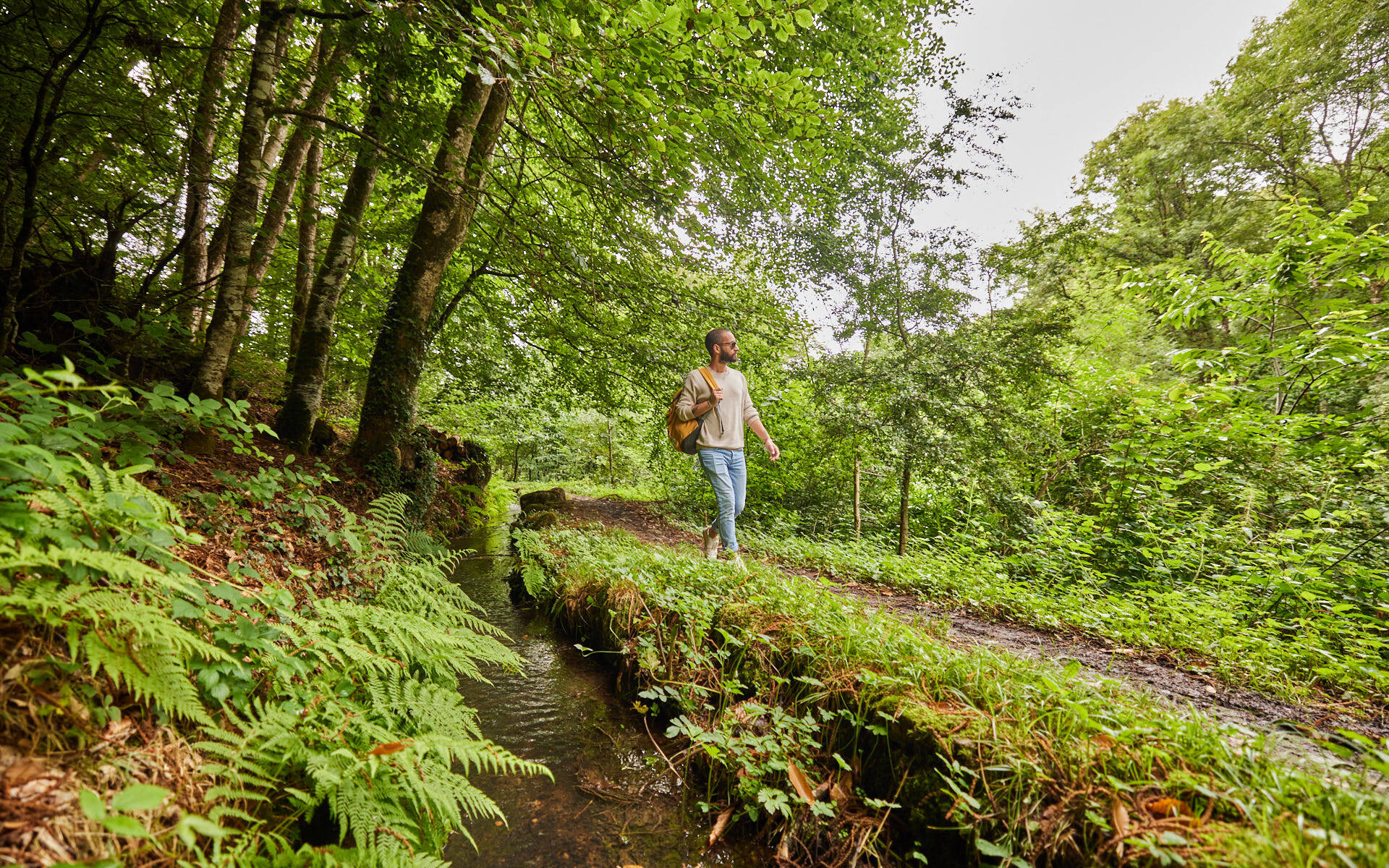 Un homme marche au bord d'un ruisseau